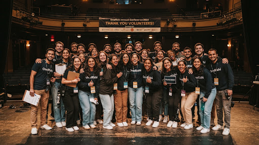 Group portrait of thirty young volunteers and event organizers gathered on stage